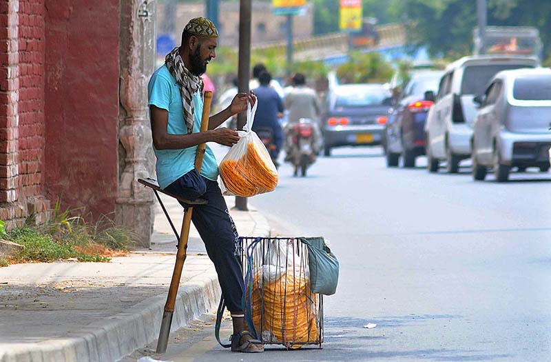 A disabled person selling edible stuff at a roadside during hot and humid weather