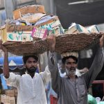 Labourers carrying baskets of wooden boxes on their heads to earn a livelihood at a Fruit Market in the city