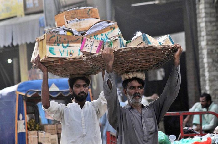 Labourers carrying baskets of wooden boxes on their heads to earn a livelihood at a Fruit Market in the city