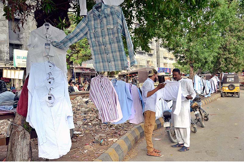 A vendor selling used shirts at his roadside setup