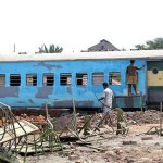 A worker is painting a train carriage with the purpose of transforming it into a functional and inviting hotel at Damdama.