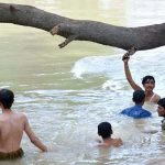 Youngsters enjoy in the water canal to get relief from hot weather in the city