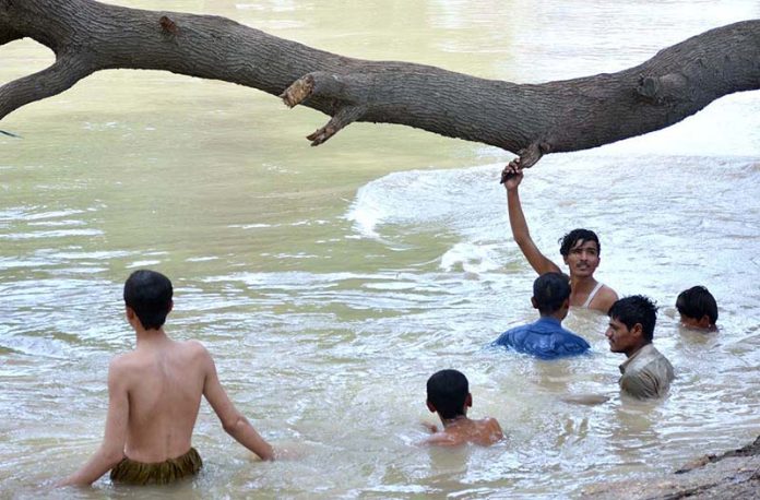 Youngsters enjoy in the water canal to get relief from hot weather in the city