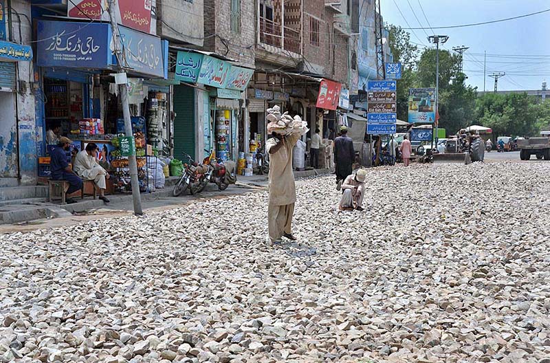 Laborers spreading stones at the road construction of Ali Chowk during development work in the city