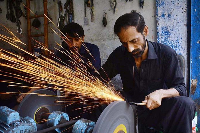 A blacksmith sharpening knives to be used during the procession of Muharram