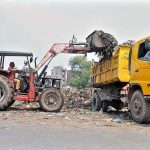 Staffer of Waste Management loading garbage on truck