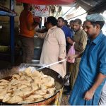 People throng at a samosa shop after heavy rains in the city
