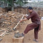 A vendor busy in cutting wood through Saw for selling purpose in upcoming winter seoson at his work place