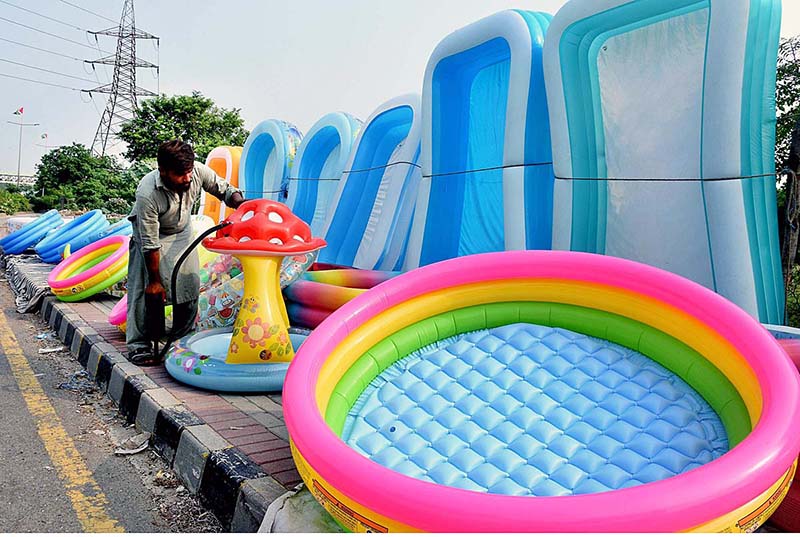 A vendor filling air in the plastic bath tubs for children displayed on footpath to attract the customers at Shaukat Ali Road in the city