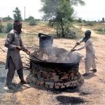 Workers mixing gravel, cement and other materials to fill damaged parts of road
