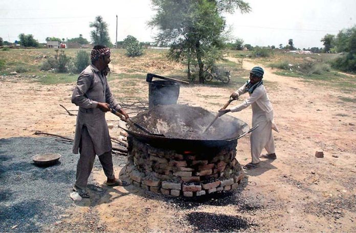 Workers mixing gravel, cement and other materials to fill damaged parts of road