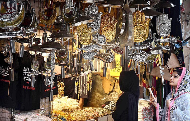 Women selecting and purchasing Muharram-ul-Harram related stuff displaying from shopkeeper at Bibi Pak Daman