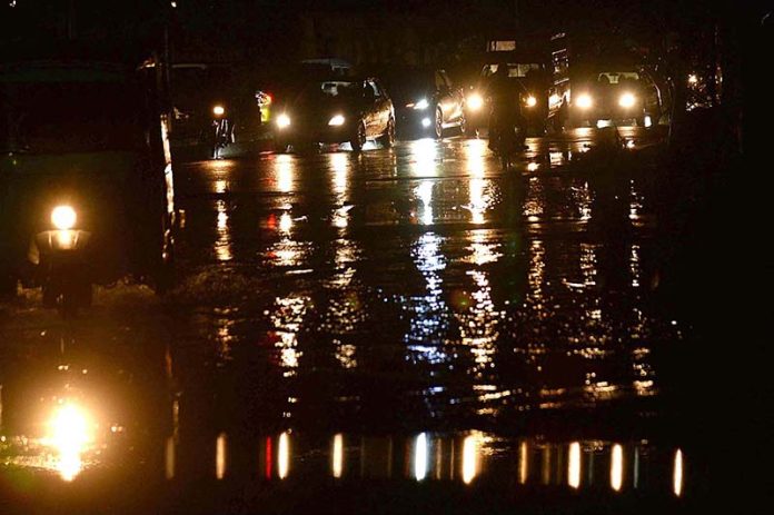 A view of reflections of vehicle’s headlights in water accumulated on road after heavy rain that experienced the Provincial Capital