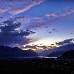 An eye catching view of sun rays peeping through clouds during sunset over the sky