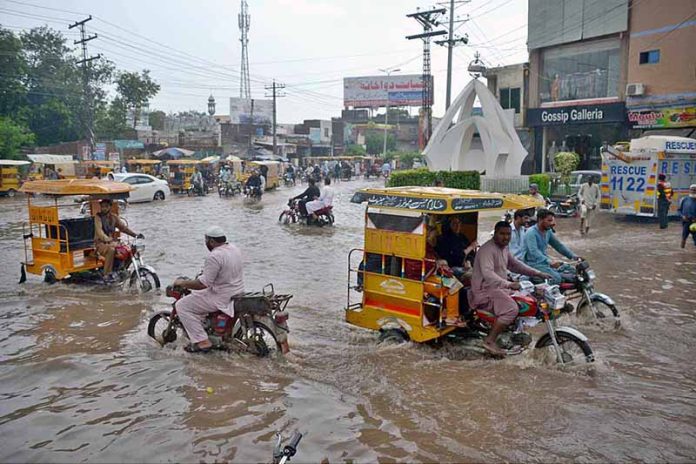 Vehicles passing through accumulated rain water after heavy monsoon rain at Committee chowk main Jhang road