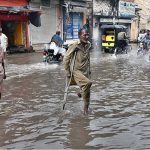 A disable old person passing through rain water accumulated on road after heavy rain that experienced the city