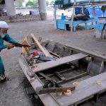 An elderly man is preparing a wooden boat near the Ravi River