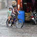 Children are riding bicycles during heavy rain in the city
