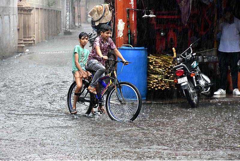 Children are riding bicycles during heavy rain in the city