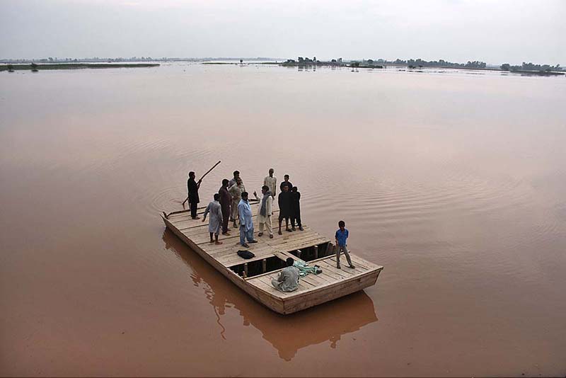 People cross flood water on a boat after river Ravi water entered in their houses at Village Naul Manga Mandi 30 Kilometer from the Provincial Capital