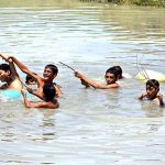 Youngsters bathing in water pond to get relief from scorching hot weather