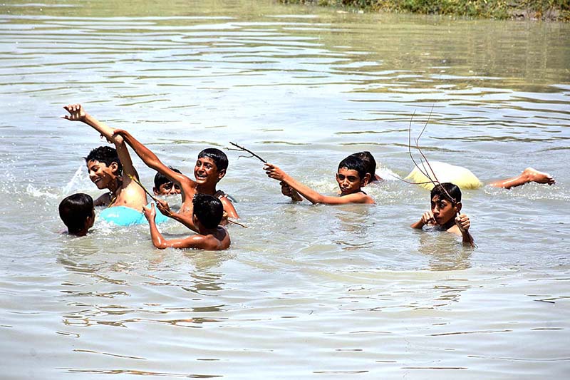 Youngsters bathing in water pond to get relief from scorching hot weather