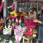 A shopkeeper is busy in making flower garlands to attract the customers at Lohari Chowk