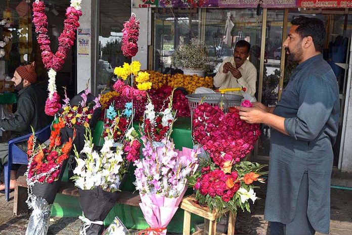 A shopkeeper is busy in making flower garlands to attract the customers at Lohari Chowk