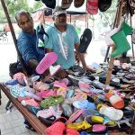 A vendor arranging and displaying used shoes to attract the customers at roadside stall