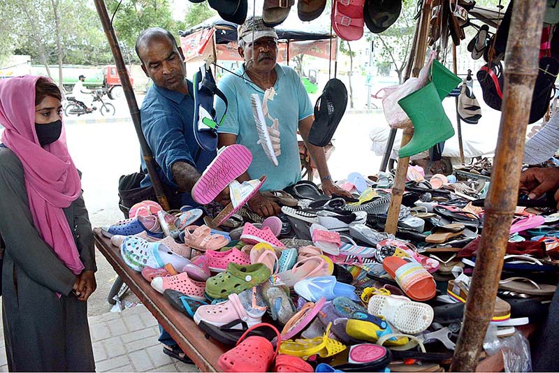 A vendor arranging and displaying used shoes to attract the customers at roadside stall