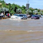 Vehicles passing through rain water accumulated on the road during rain that experienced in the city