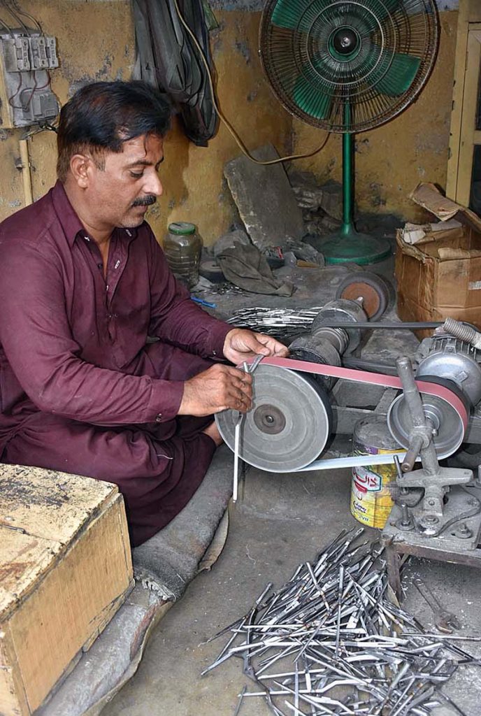 A skilled worker manufacturing export quality surgical instruments at his work place