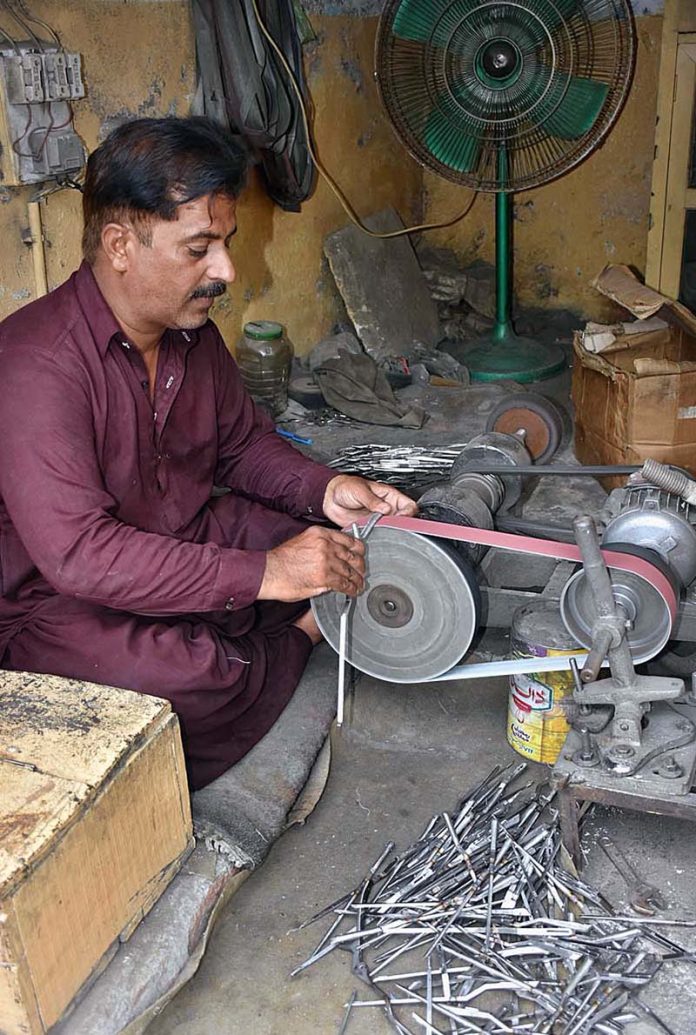 A skilled worker manufacturing export quality surgical instruments at his work place