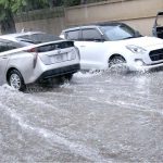 Vehicles are passing through the water during heavy rain in the city
