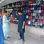 A vendor selling caps to attract customers at his roadside setup