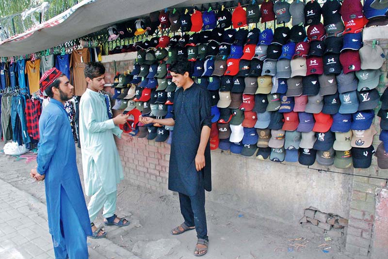 A vendor selling caps to attract customers at his roadside setup