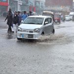 Commuters passing through rain water accumulated during heavy rain