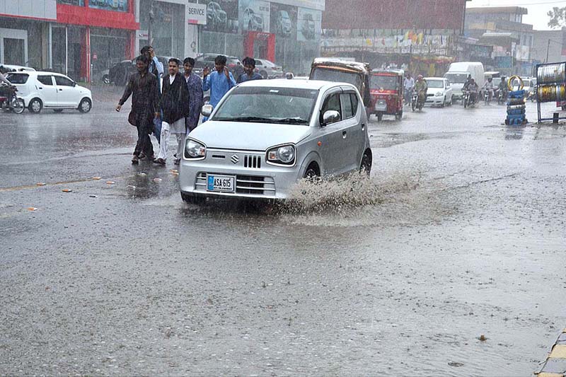 Commuters passing through rain water accumulated during heavy rain