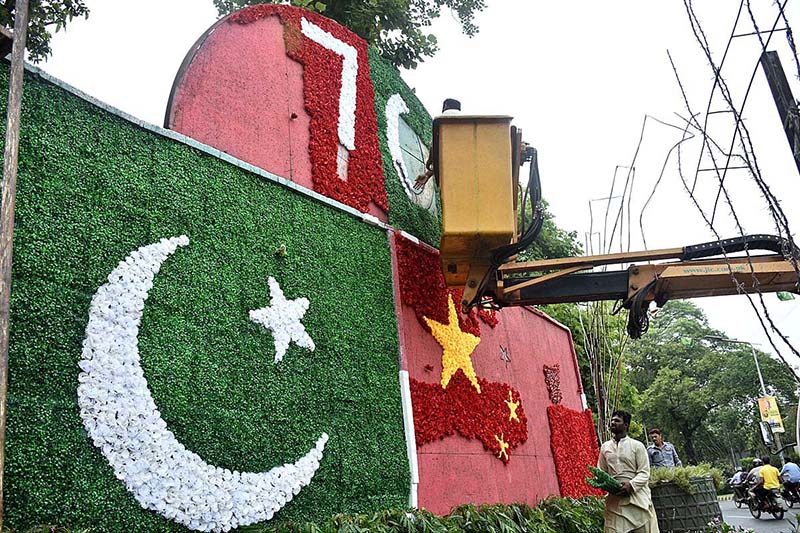 PHA workers decorate the sign board with artificial flowers and preparing the Pakistan and China flags to mark the 76 years of Pak-China Friendship at Mall Road
