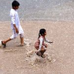 Children enjoying play in rain water on the road at Ghouri Town