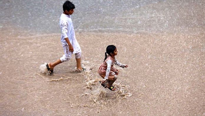 Children enjoying play in rain water on the road at Ghouri Town