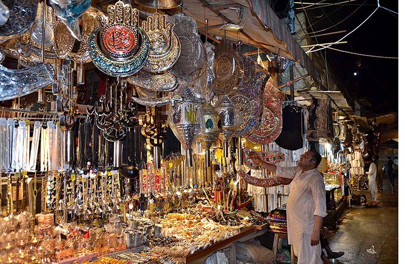 A woman purchasing Ashura related stuff at a shopkeeper’s setup in Bibi Pak Daman