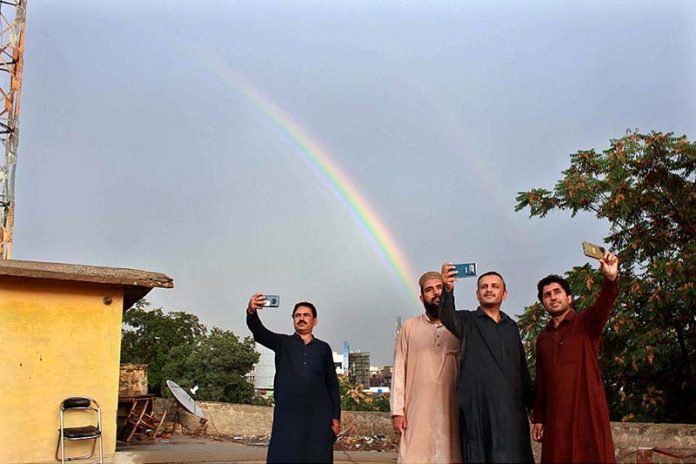 People taking selfie with rainbow as the city receives rain turned weather pleasant