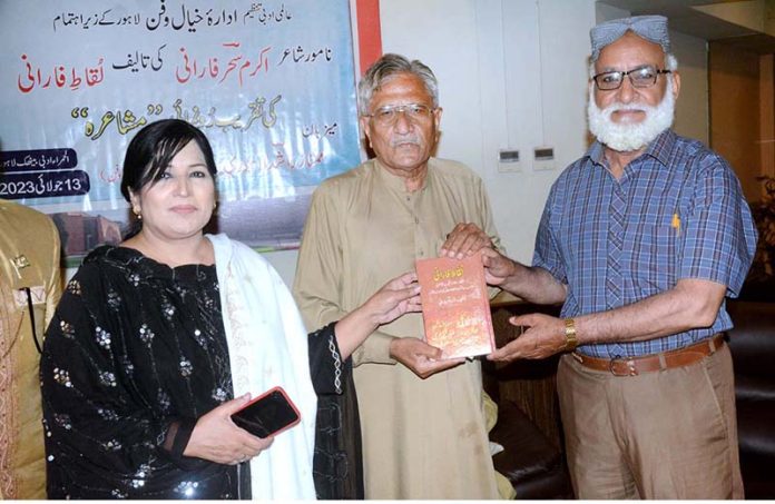The book writer Akram Sahar Farani gives away his book to a person during the literary session Mushaira and the launch of his book at Al Hamra Arts Council