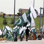 A vendor displaying national flags to attract customers at Koral chowk