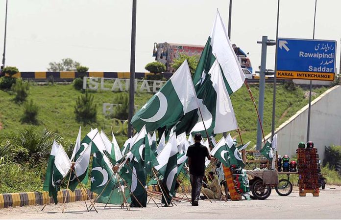 A vendor displaying national flags to attract customers at Koral chowk