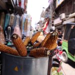A vendor selling roasted corn cobs to attract customers at his roadside setup in the city