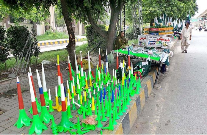A vendor displaying national flags and other stuffs related to Independence Day celebrations on Murree Road