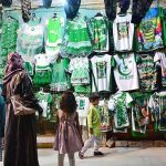 Family busy in selecting and purchasing National flag related stuff from vendor in connection with Pakistan Independence Day celebrations