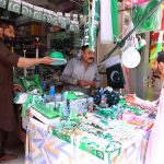 A vendor displaying and selling 14th August related stuff to attract customers at his roadside setup in the city
